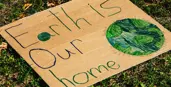  a cardboard sign that says earth is our home